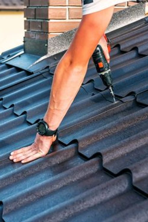 a professional master (roofer) with electric screwdriver covers repairs the roof